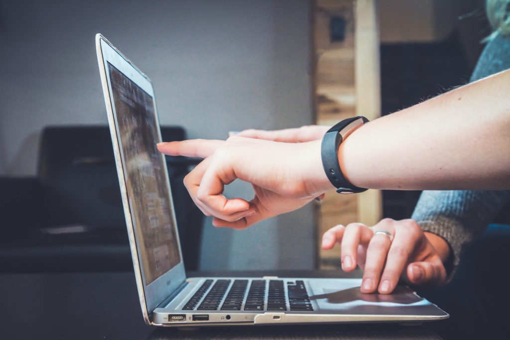 personas apuntando una pantalla de computador con la mano